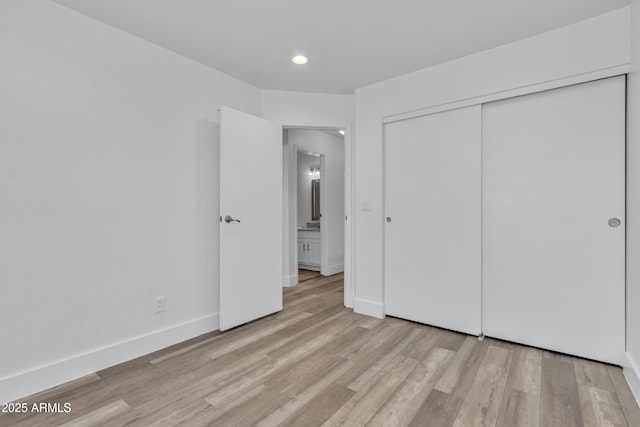 unfurnished bedroom featuring a closet, baseboards, and wood finished floors