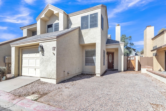 view of front facade with stucco siding, a shingled roof, a gate, fence, and a garage