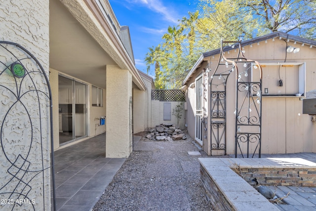 exterior space with an outbuilding, a patio area, and stucco siding