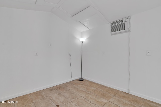 spare room featuring light tile patterned floors, a wall mounted air conditioner, and baseboards