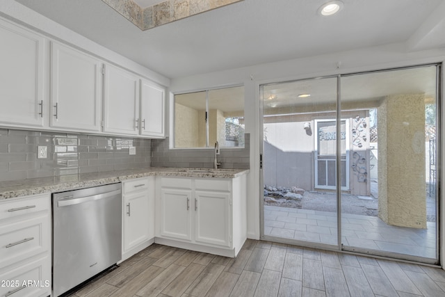 kitchen with dishwasher, tasteful backsplash, white cabinetry, and light stone countertops