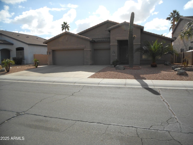 view of front facade with concrete driveway, an attached garage, a tile roof, and stucco siding