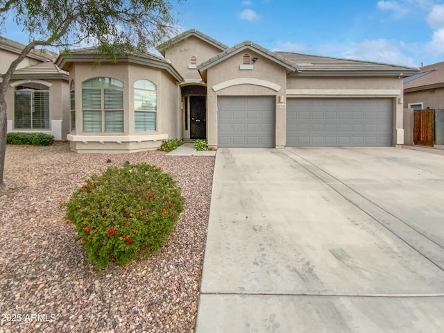 view of front of home featuring a tiled roof, a garage, driveway, and stucco siding