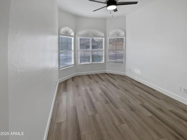 empty room featuring a ceiling fan, baseboards, and wood finished floors