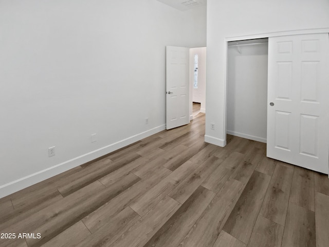 unfurnished bedroom featuring a closet, baseboards, and wood finished floors