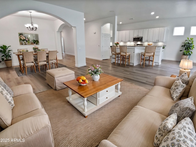 living room featuring light wood-style flooring, recessed lighting, arched walkways, and baseboards