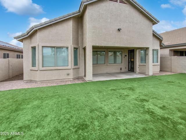 back of property with stucco siding, a yard, and fence