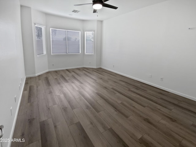 empty room with baseboards, wood finished floors, visible vents, and ceiling fan