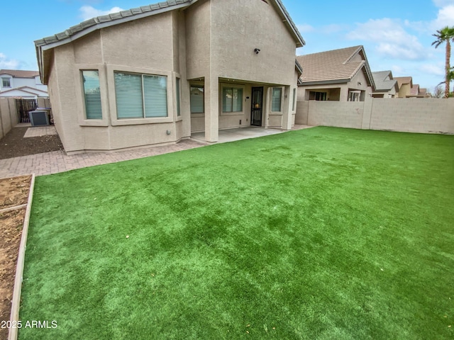 back of property with a tile roof, stucco siding, a fenced backyard, a yard, and a patio