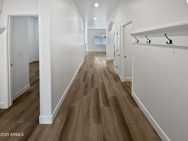 hallway with recessed lighting, wood finished floors, baseboards, and arched walkways