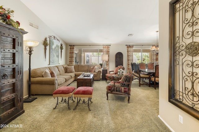 carpeted living room with a wealth of natural light, lofted ceiling, and a notable chandelier