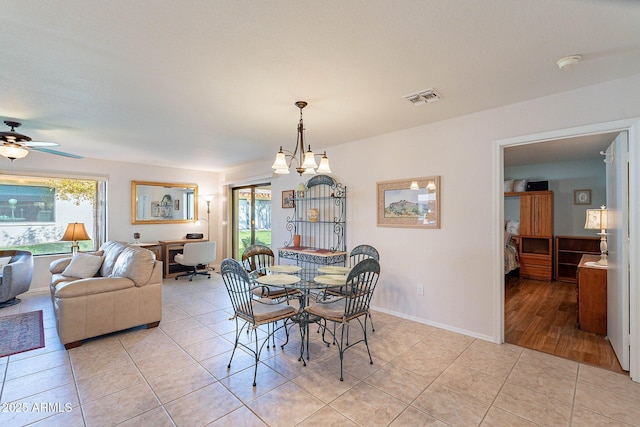 dining area featuring plenty of natural light, light tile patterned flooring, and ceiling fan with notable chandelier