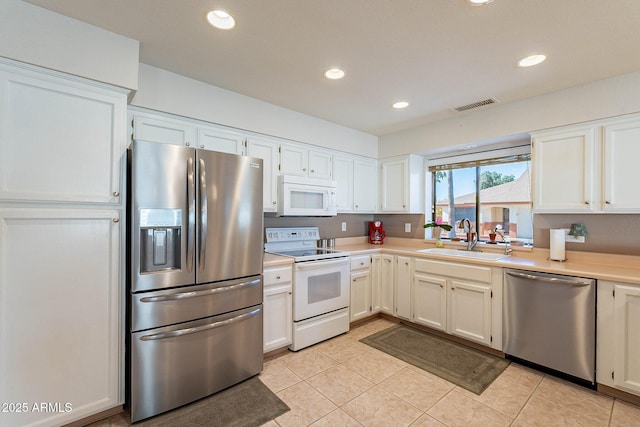 kitchen with light tile patterned flooring, appliances with stainless steel finishes, white cabinetry, and sink