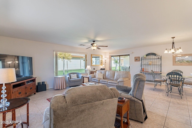 living room featuring plenty of natural light, light tile patterned flooring, and ceiling fan with notable chandelier