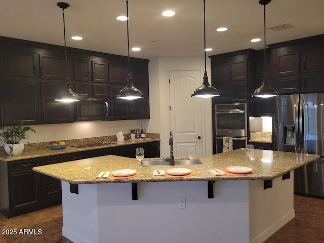 kitchen featuring appliances with stainless steel finishes, a kitchen bar, a sink, and decorative light fixtures