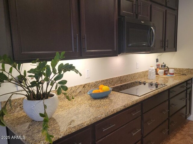 kitchen featuring light stone counters, dark brown cabinets, and black electric cooktop