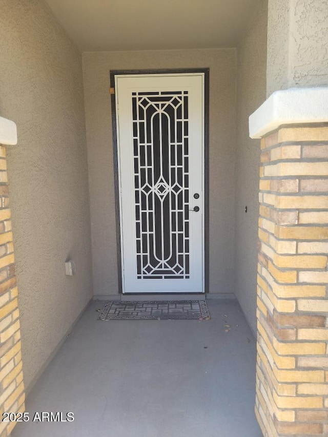 view of exterior entry with brick siding and stucco siding