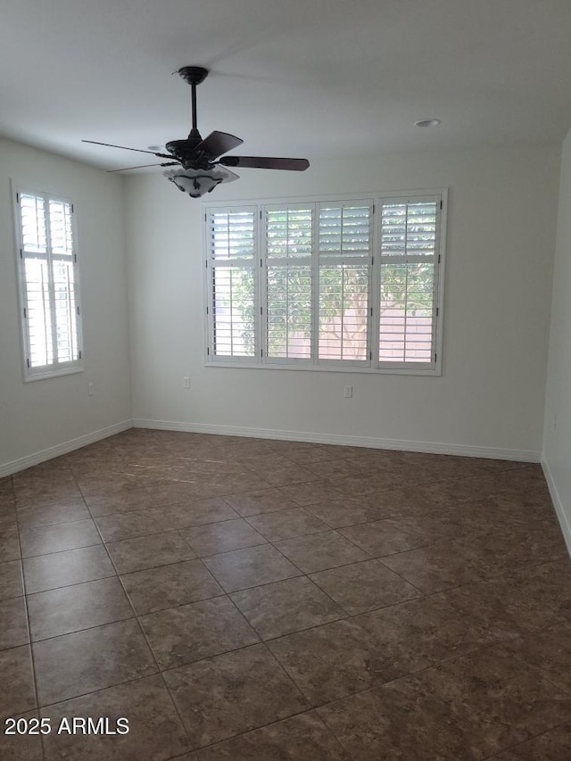 spare room featuring dark tile patterned flooring, ceiling fan, and baseboards