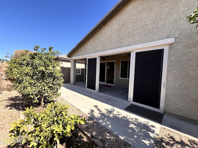 rear view of property featuring fence, a patio, and stucco siding