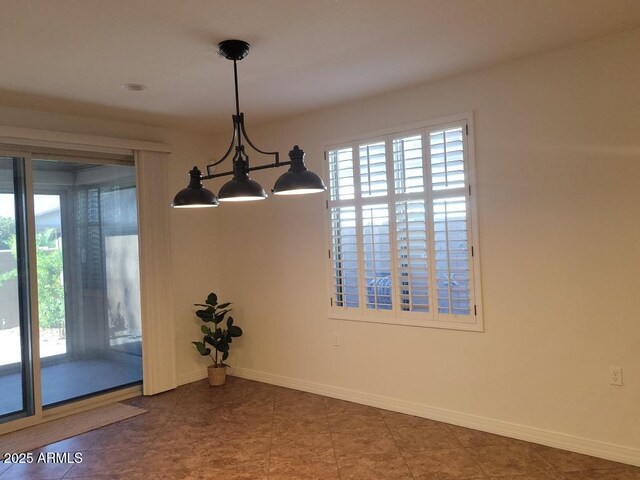 spare room featuring an inviting chandelier, baseboards, and a wealth of natural light