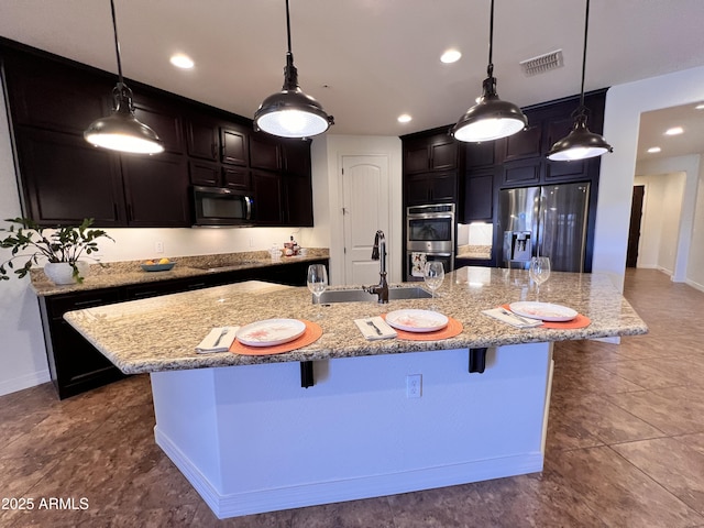 kitchen with visible vents, light stone counters, black appliances, a kitchen bar, and a sink