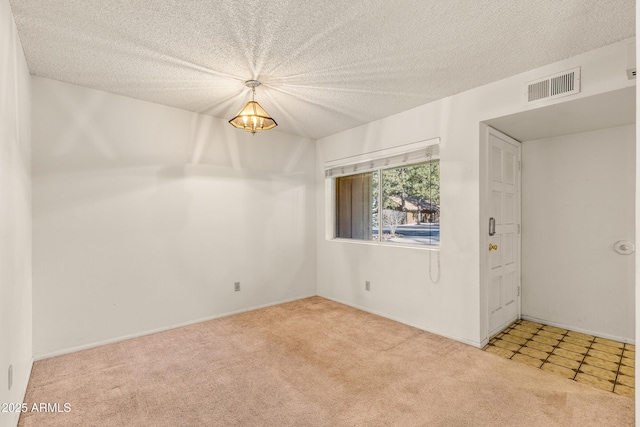 spare room with light colored carpet, a textured ceiling, and a notable chandelier