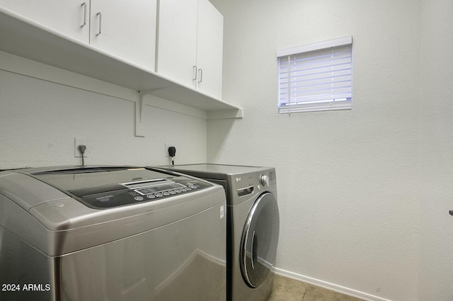 laundry room with cabinets, light tile patterned floors, and washing machine and dryer