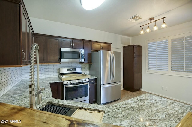 kitchen with decorative backsplash, appliances with stainless steel finishes, light stone counters, dark brown cabinetry, and light tile patterned flooring