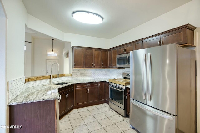 kitchen with sink, hanging light fixtures, light stone countertops, appliances with stainless steel finishes, and kitchen peninsula