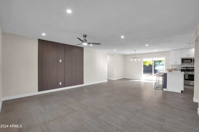 unfurnished living room featuring ceiling fan with notable chandelier