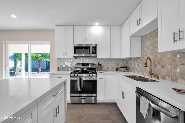 kitchen with white cabinetry, sink, light stone counters, and stainless steel appliances