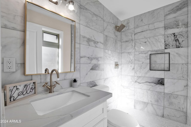 bathroom with tile walls, vanity, toilet, and a tile shower