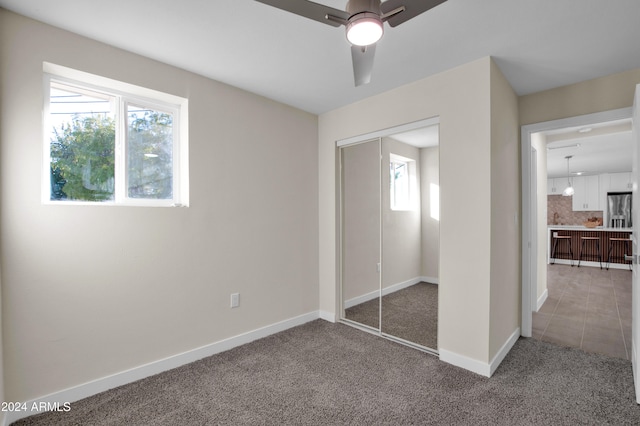 unfurnished bedroom featuring carpet floors, ceiling fan, stainless steel fridge with ice dispenser, and a closet