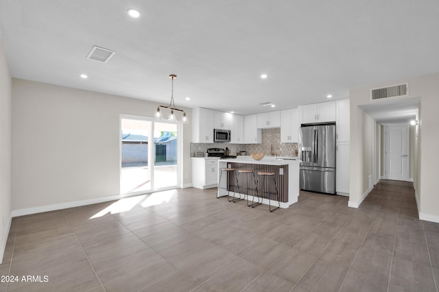 kitchen featuring stainless steel appliances, a kitchen island, pendant lighting, a kitchen breakfast bar, and white cabinets