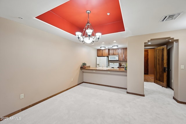 interior space featuring a chandelier, a raised ceiling, visible vents, and light colored carpet