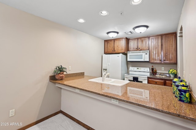 kitchen featuring a peninsula, white appliances, a sink, and recessed lighting