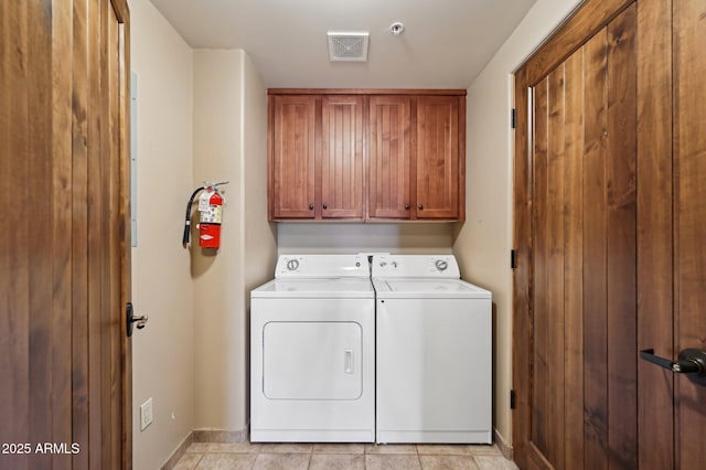 clothes washing area with visible vents, washing machine and dryer, cabinet space, and baseboards