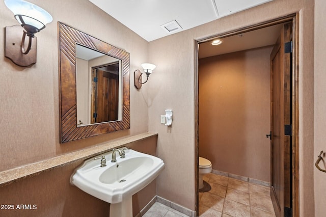 bathroom featuring tile patterned flooring, toilet, a sink, visible vents, and baseboards