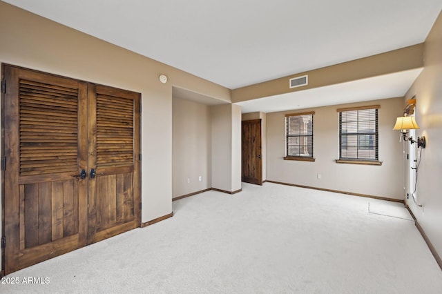 spare room with baseboards, visible vents, and light colored carpet