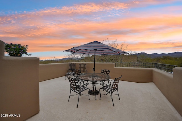 patio terrace at dusk featuring a mountain view and a balcony