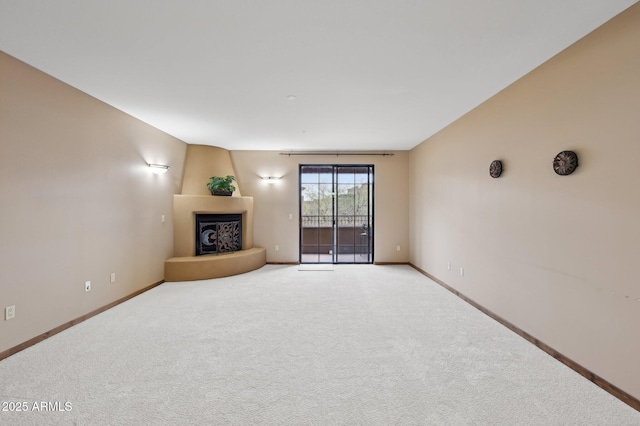 unfurnished living room with a large fireplace, baseboards, and light colored carpet