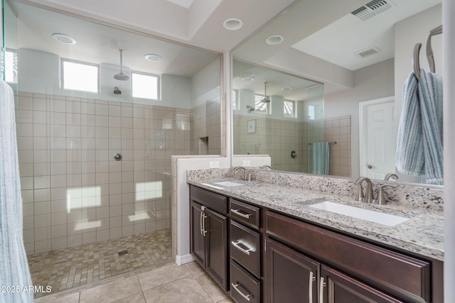 bathroom featuring vanity, a tile shower, and tile patterned floors