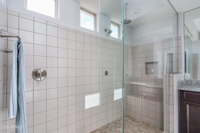 bathroom featuring a shower with door and vanity