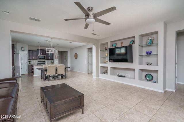 tiled living room with ceiling fan and built in features