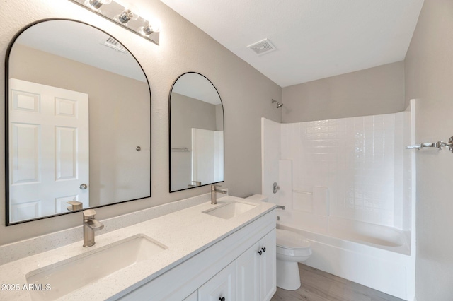 bathroom featuring a sink, washtub / shower combination, toilet, and double vanity