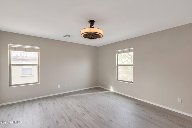 unfurnished room with visible vents, baseboards, and wood finished floors
