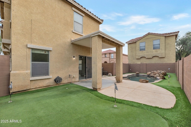 back of house featuring a fenced backyard, stucco siding, a patio, and a fenced in pool