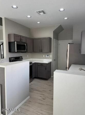 kitchen with light wood finished floors, visible vents, gray cabinetry, light countertops, and appliances with stainless steel finishes