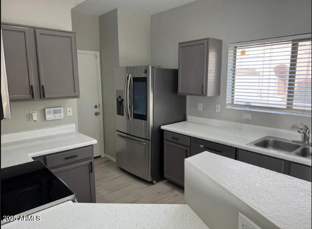 9621 N 82nd Ln, Peoria, AZ 85345 - kitchen with gray cabinetry, light wood-style flooring, a sink, and appliances with stainless steel finishes