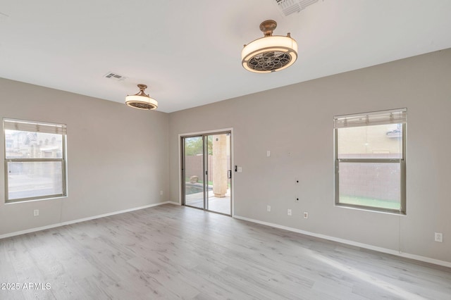 unfurnished room featuring light wood-style flooring, baseboards, and visible vents